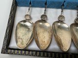 three silver spoons in a box with a blue cloth