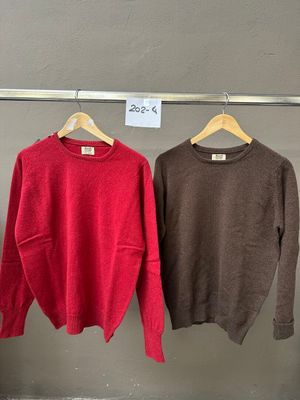 trois pulls suspendus à un portant dans un magasin de vêtements