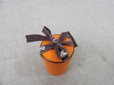 a small orange box with a brown ribbon on it