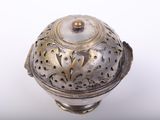 a silver and gold vase with a lid on a white surface