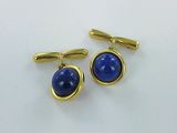 a close up of a pair of blue cufflinks on a white surface