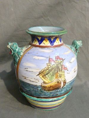 a vase with a ship painted on it sitting on a table