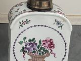 un récipient blanc orné de fleurs, posé par terre
