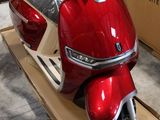 un scooter rouge posé sur un chariot devant une boîte