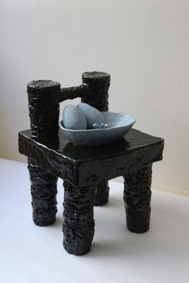 une petite chaise noire sur laquelle est posé un bol