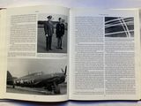 a book open to a picture of two men standing in front of an airplane