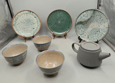 five bowls and a teapot sitting on a table
