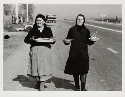 black and white photograph of two women holding plates of food