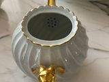 a white and gold teapot sitting on a marble table