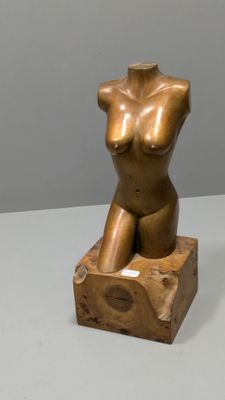 sculpture représentant un torse féminin assis sur un bloc de bois