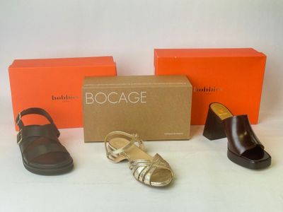 trois paires de chaussures et une boîte de boîtes orange posées sur une surface blanche