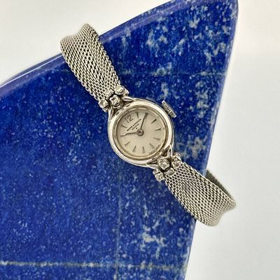 an image of a wrist watch sitting on top of a blue stone