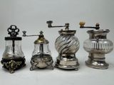 three silver and glass coffee grinders and one with a wooden handle