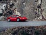 a red sports car driving down the road next to a cliff