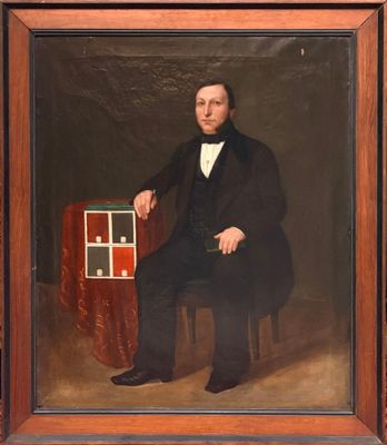 portrait d'un homme en costume noir et nœud papillon, assis sur une chaise