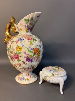 a white vase with a gold handle and a small stool