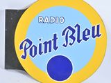 enseigne « Radio Point Bleu » sur un mur blanc, avec un point bleu