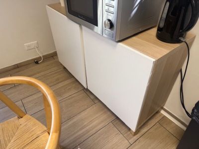 un micro-ondes posé sur un meuble, à côté d'une chaise