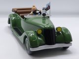 a green toy car with a teddy bear in the back seat