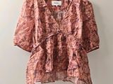an image of a pink blouse hanging on a hanger