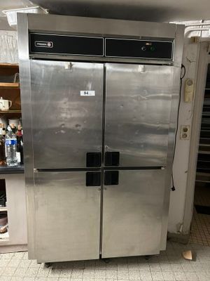 a stainless steel refrigerator in a kitchen with a lot of clutter on the floor