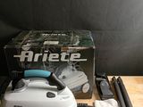 un fer à repasser à vapeur posé sur une table en bois, à côté d'une boîte noire et blanche