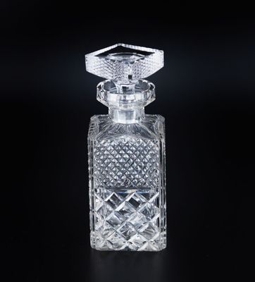 un gros plan d'un flacon de parfum en verre transparent posé sur une surface noire