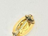 a gold pin with a bird on it on a white surface