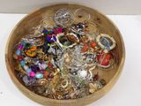 a wooden bowl filled with assorted jewelry on a table