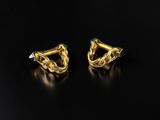 a pair of gold earrings on a black surface