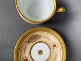 two cups and saucers with gold rims on a gray surface