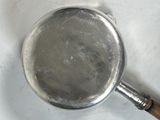 a silver pan with a wooden handle sitting on a table