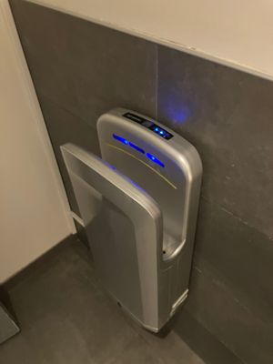 a urinal in the corner of a bathroom with a blue light on it