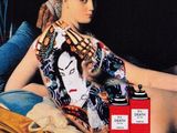a painting of a woman sitting on a bed with a bottle of perfume