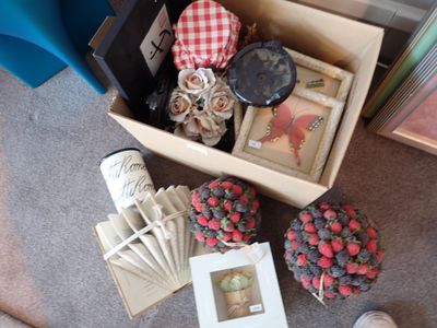 une boîte contenant divers objets, posée par terre à côté d'une paire de chaussures