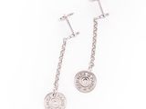 une paire de boucles d'oreilles avec une pièce de monnaie suspendue à une chaîne