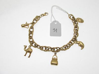 un gros plan d'un bracelet en or orné de breloques sur fond blanc