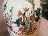 a white vase with a painting on it sitting on a table