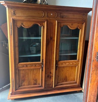 une armoire en bois avec des portes vitrées et une horloge posée dessus
