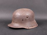 an old helmet with holes on the side of it on a black surface