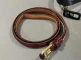 a brown belt with a gold buckle on a table