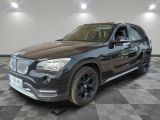 La BMW X1 est garée dans un garage dont le sol est recouvert d'un motif à damier.