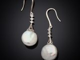 une paire de boucles d'oreilles en perles et diamants sur fond noir