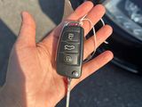 une main tenant une clé de voiture, avec une voiture en arrière-plan