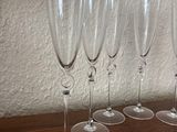 several empty wine glasses lined up on a table in front of a white wall