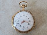 une petite montre de poche en or avec des chiffres romains