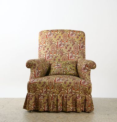 an upholstered chair in a room with a white wall behind it