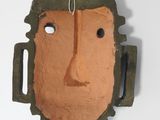 a clay mask hanging on the wall of a room