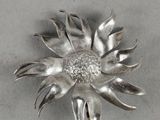 a silver brooch with a flower on it
