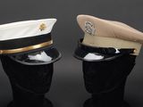 pair of military hats on mannequin heads on black background